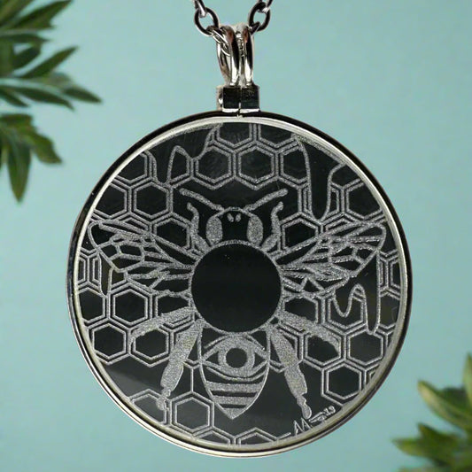 Necklace with a circular pendant featuring a bee and honeycomb pattern on a white background